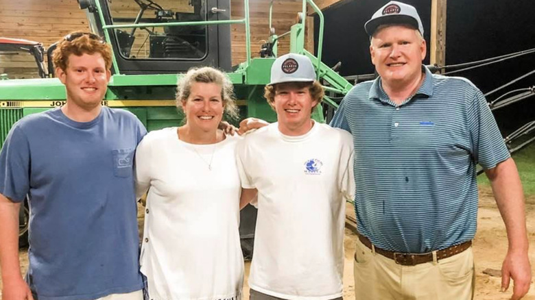 The Murdaugh family pose for a photo in a barn in front of a tractor