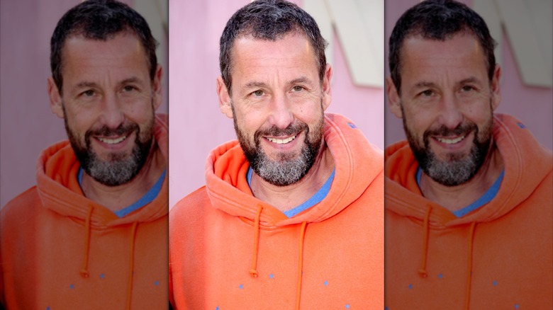 Adam Sandler wearing an orange and blue sweatshirt.