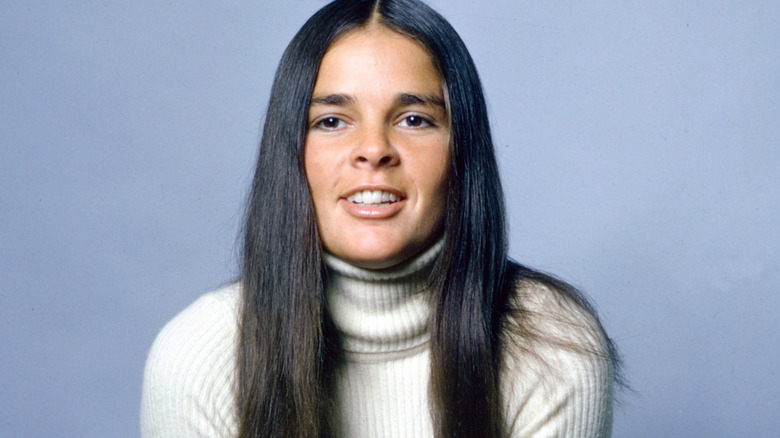 Ali MacGraw smiling in front of a blue background