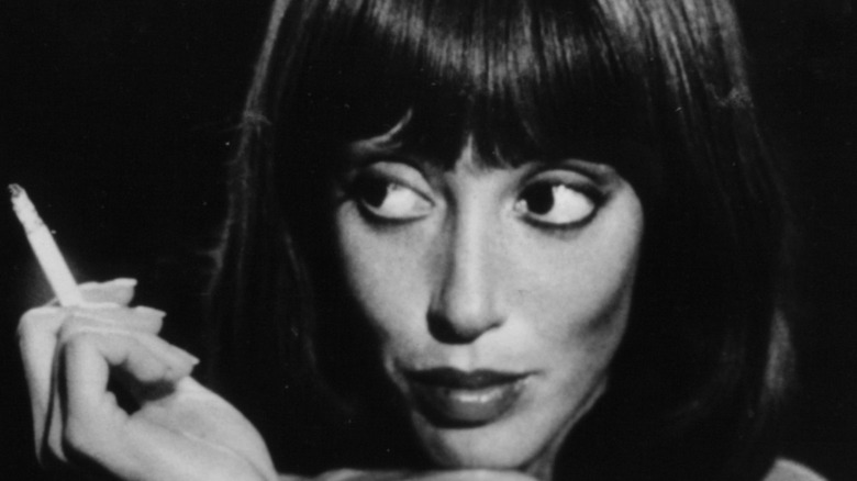 Shelley Duvall looking sideways while holding a cigarette