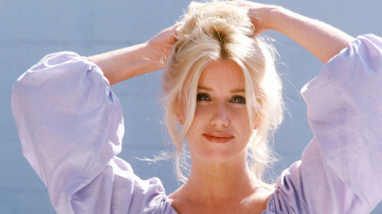 Suzanne Somers wearing a purple top, fixing her hair