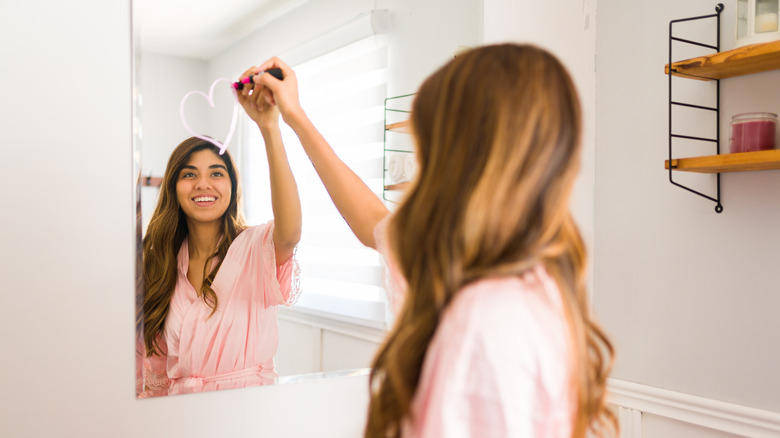 Woman drawing a heart on the mirror