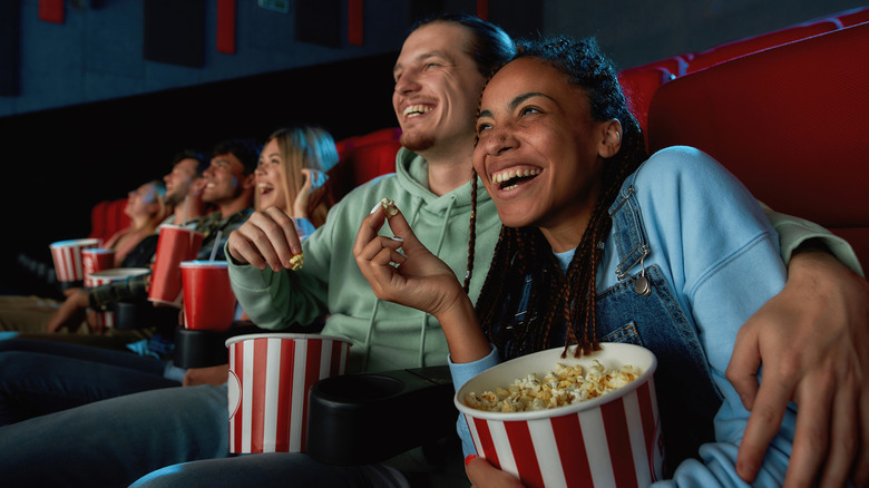 couple cuddles in movie theater while eating popcorn