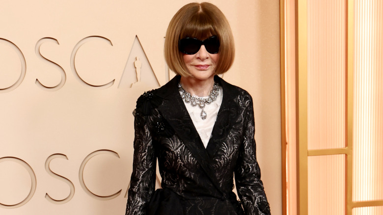 Anna Wintour posing on the red carpet with her sunglasses on