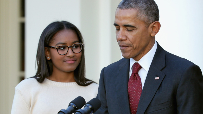 Sasha Obama smiling at Barack Obama as he speaks