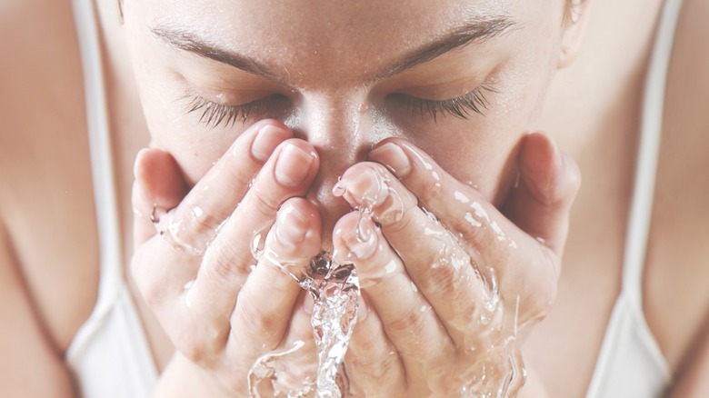 Woman splashes face with water