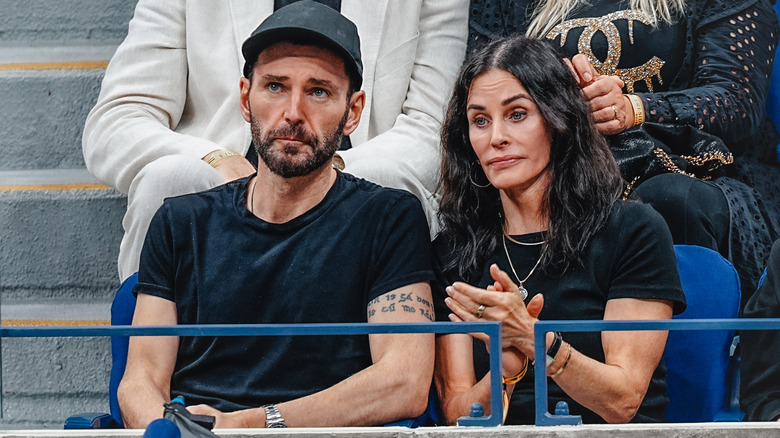 Johnny McDaid and Courteney Cox applauding in the stands at the 2025 US Open