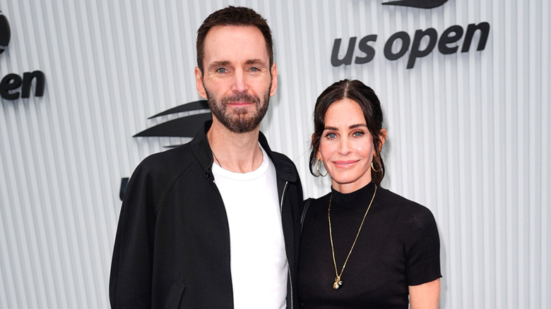 Johnny McDaid and Courteney Cox smiling while posing together at the 2025 US Open