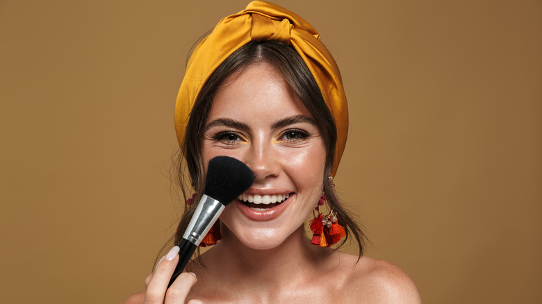 Woman smiling using makeup brush