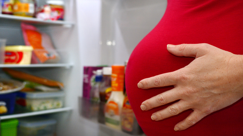 Pregnant woman looking in refrigerator 