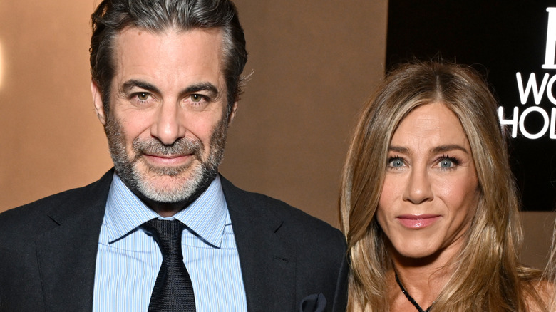 A smiling Jennifer Aniston standing next to Jim Curtis