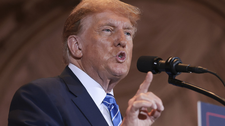 Donald Trump speaking into microphone, pointing with hand