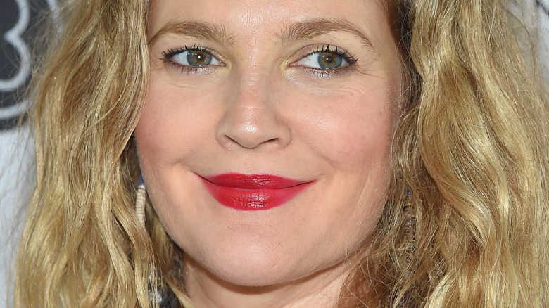 Drew Barrymore posing at event with slight smile and red lipstick