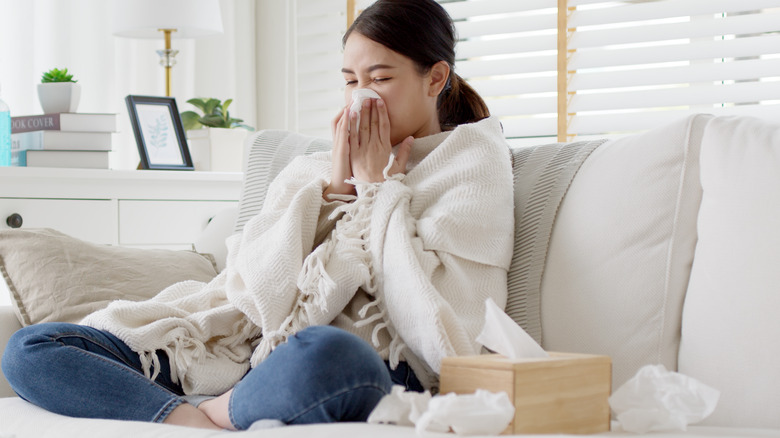 girl blowing nose on couch