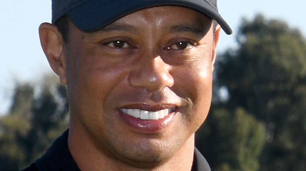 Tiger Woods smiling in a black baseball cap