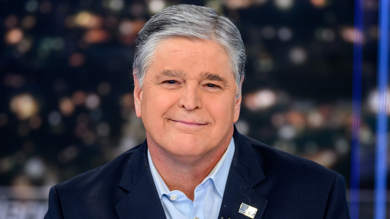 Sean Hannity wearing a blazer and blue collared shirt while on the set of his show 'Hannity.'