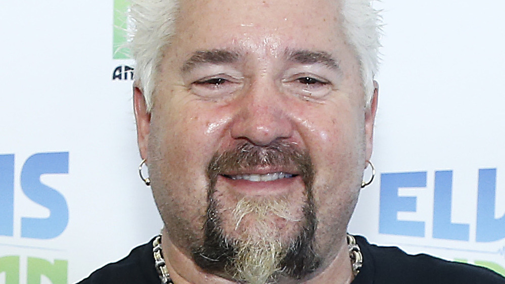 Guy Fieri smiling with earrings and facial hair