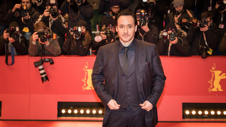 John Cusack walking a red carpet in front of a throng of photographers in 2016.