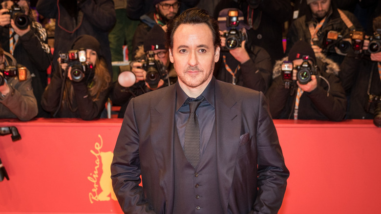 John Cusack walking a red carpet in front of a throng of photographers in 2016.