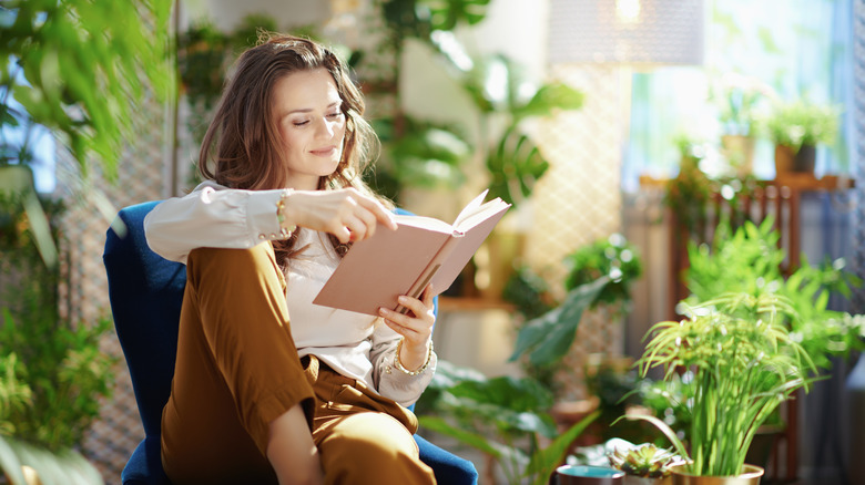 woman happily reading in room with many plants