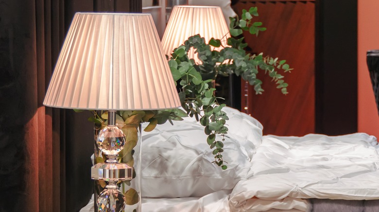 Side view of bed with pleated lamps on both side tables