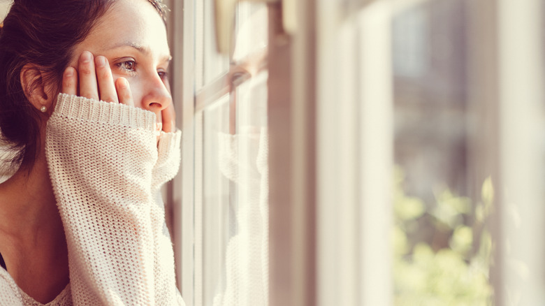 Woman looking out window nostalgically 