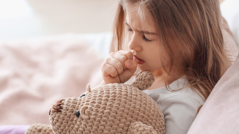 Girl coughing in bed teddy bear