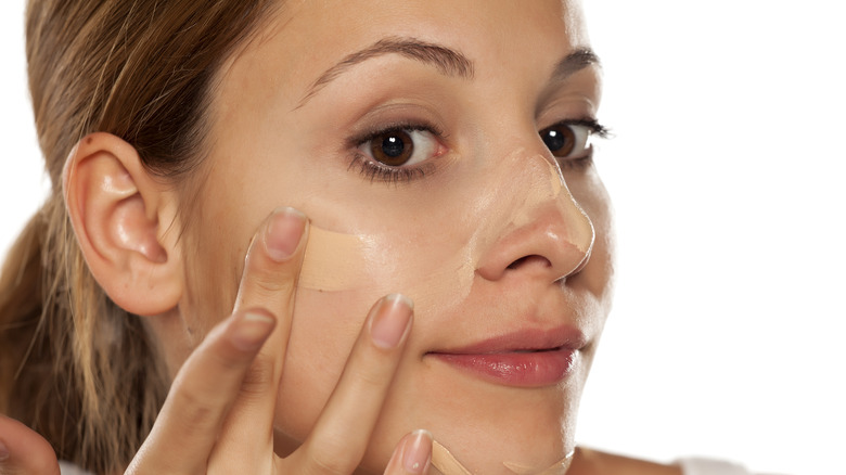 A woman applying foundation to her face 