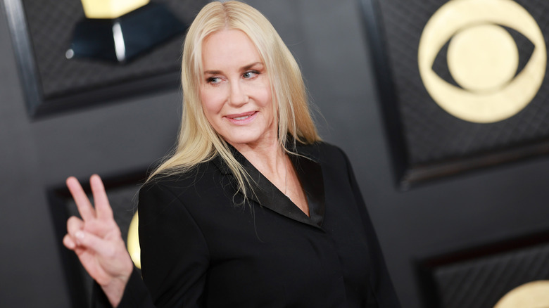Daryl Hannah smiling while making a peace sign in a black blazer