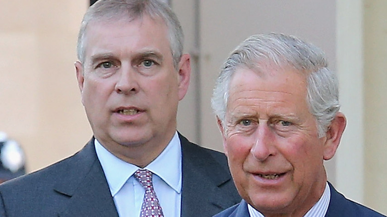 Prince andrew and king charles with heads bowed