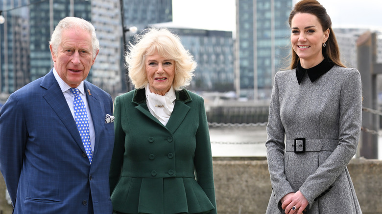 A smiling King Charles III and Queen Camilla pictured posing outdoors with Princess Catherine