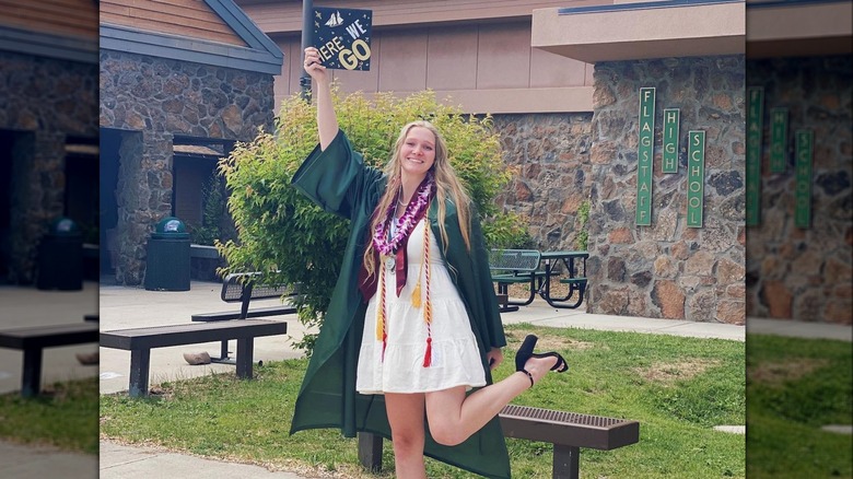 Ysabel Brown holding graduation cap in the air