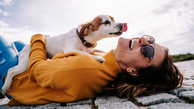 Woman laughing while holding a dog