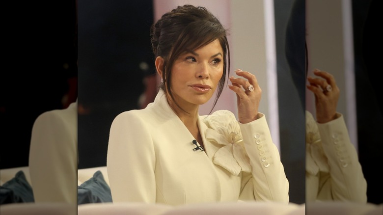 Lauren Sánchez Bezos wears her hair in an updo and frowns as she reaches for her face.