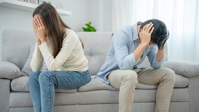 Upset couple sit away on couch