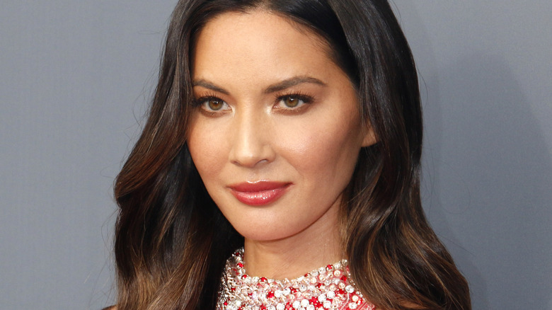 Olivia Munn smiles wearing red