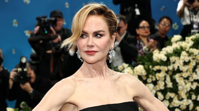 Nicole Kidman posing in front of photographers and flowers
