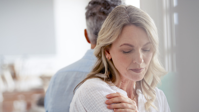 Woman looking down as man stands behind her