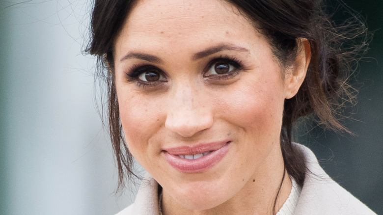Meghan Markle grinning with hair pulled back