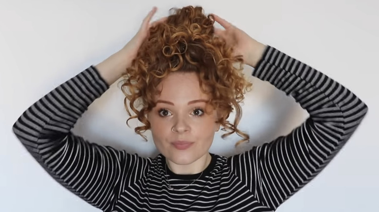 woman putting up curly red hair