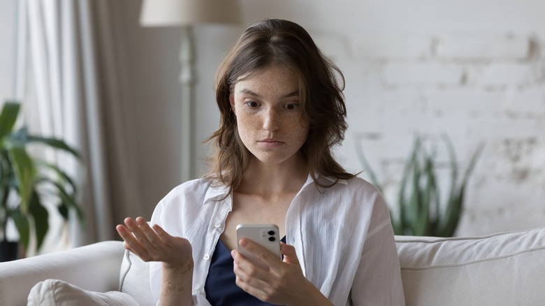 Woman looking at her phone frustrated