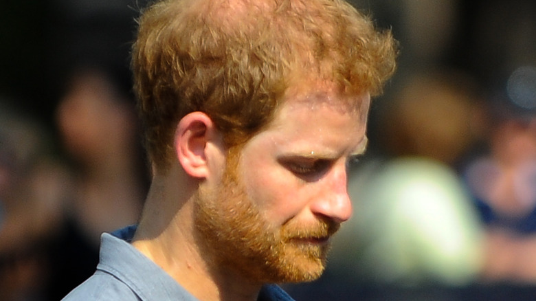 Prince Harry wears a blue collared shirt.