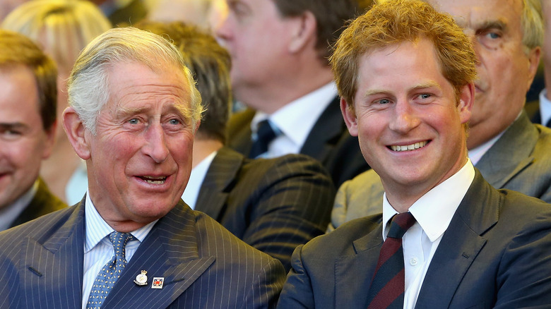 King Charles talking to Prince Harry and Harry smiling