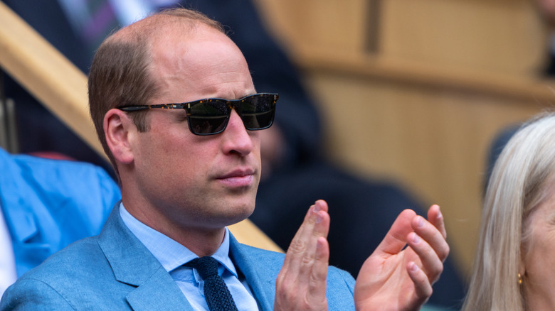 Prince William clapping at an event with sunglasses on