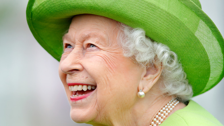 Queen Elizabeth smiling widely in an all-green outfit