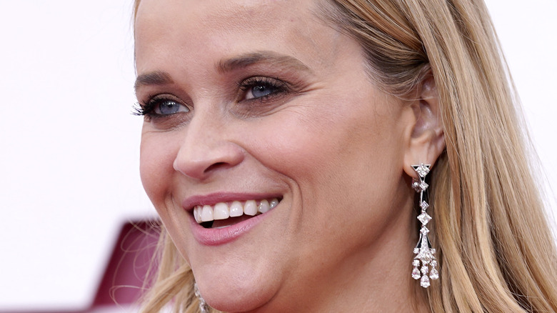 Reese Witherspoon smiling with hair down and long diamond earrings