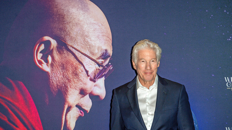 image of Richard Gere at a movie premiere with a banner showing the profile of the Dalai Lama behind him
