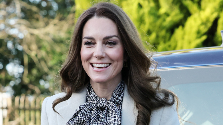 Kate Middleton smiling in white coat and black houndstooth bow