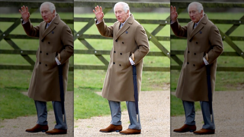 King Charles waving outdoors wearing camel coat