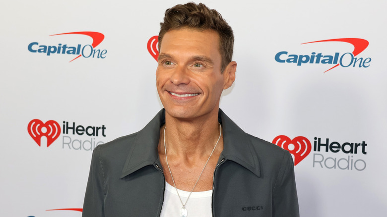 Ryan Seacrest smiling while posing at an event